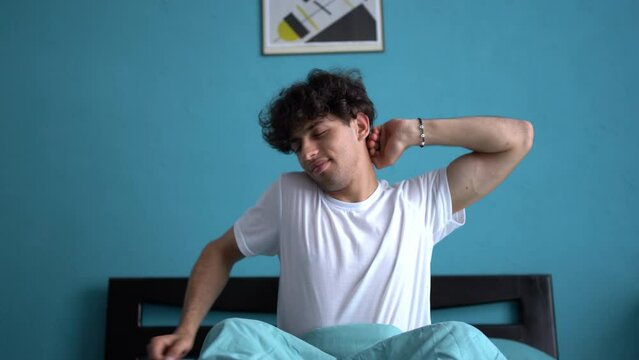Arabic man wake up in the morning in bed yawns and rubs his eyes, tired and sleepy