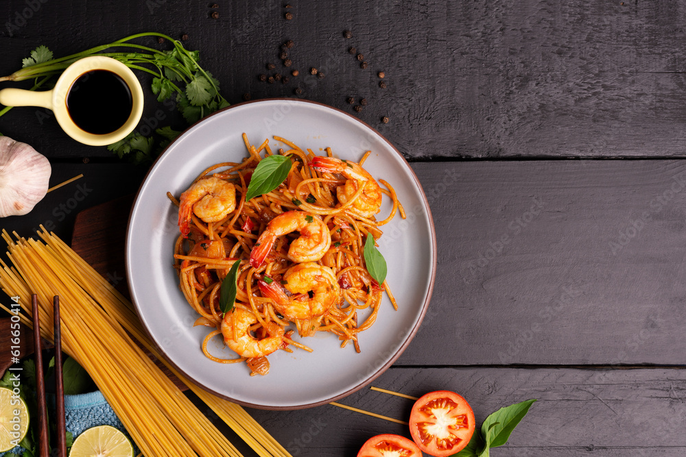 Canvas Prints fried spaghetti or fried noodles tomato sauce and prawns on a blue plate on a black wooden table top