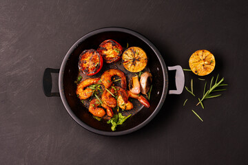 Grilled prawns served on a plate with lemon. Garlic on dark black background. Seafood. Top view.