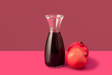 Decanter with red wine on pink background