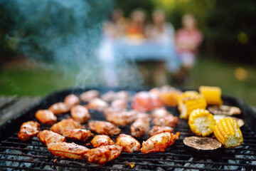 Assorted delicious grilled meat with barbecue grilled vegetables. Сompany of people gathered for barbecue in summer garden. Summer, party, adventure, youth, frienship concept