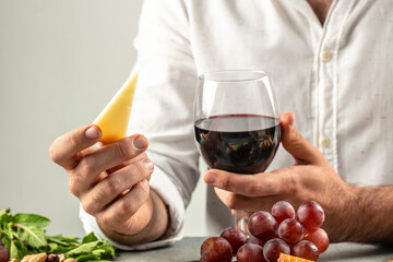 Man holding glass red wine and spanish manchego cheese. Dinner or aperitivo party concept