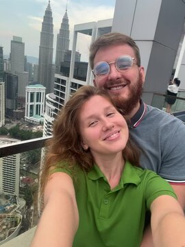 selfie of a couple in love in kuala lumpur, against the background of the towers, a happy couple travels