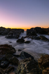 Fototapeta na wymiar Long exposure rocky seascape view with sunrise glow.