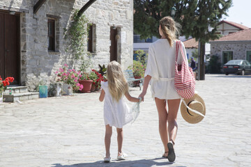 Tourist woman with her adorable little girl exploring the small Mediterranean village, concept of relaxing family summer vacation