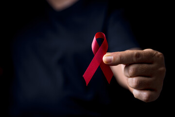 The red ribbon stick on black T-shirt. A person has a ribbon hang on shirt. The ribbon is the...
