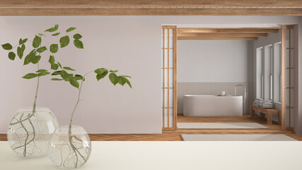 White table top or shelf with glass vase with hydroponic plant, ornament, root of plant in water, branch in vase, minimal japandi bathroom, minimal interior design