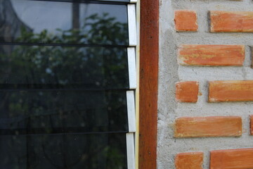 Louver window black  glass and a wall with orange bricks.