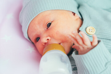 Mom feeds a newborn baby with a bottle at home