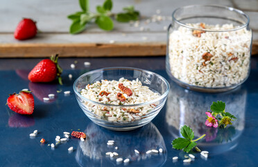 Fototapeta na wymiar Risotto raw mix with strawberries and herbs in a glass bowl and container, fresh strawberries, sage leaves over glass dark blue background
