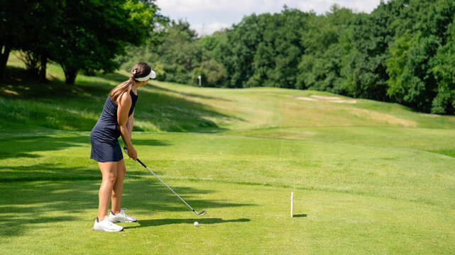 Golfer sport course golf ball fairway. People lifestyle woman playing game golf and hitting go on green grass river. Female player game shot in summer. Copy space banner