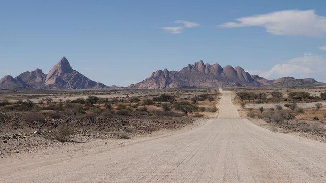 4K Spitzkoppe mountain from namibian gravel road in Namibia, Africa. African ancient rock formations, red rock landscape. Savannah wild nature. Summer sunny day. Hiking.