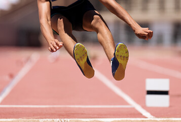 Male athlete performing a long jump during a competition at stadium