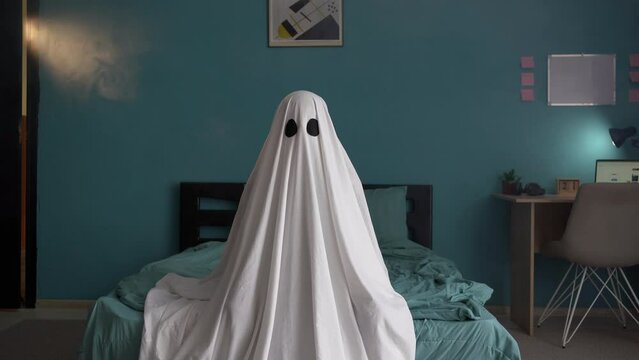 Ghost in new house with smoke sitting on bed and looking at camera, spooky halloween concept