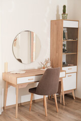 modern interior of bedroom, dressing table with mirror and soft upholstered chair. trendy minimal style decor. vertical shot. 