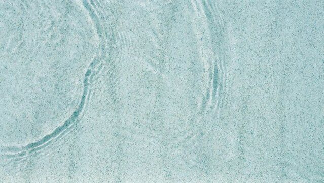 abstract white sand beach with transparent water wave from above, calm rippled water surface background concept with space for text or product presentation