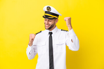 Airplane caucasian pilot isolated on yellow background celebrating a victory