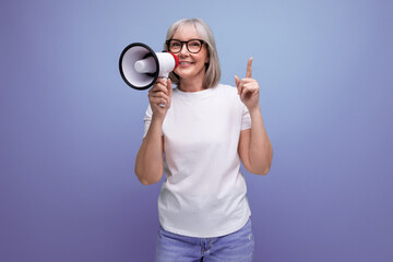 60s woman with gray hair speaks into a megaphone on a studio background