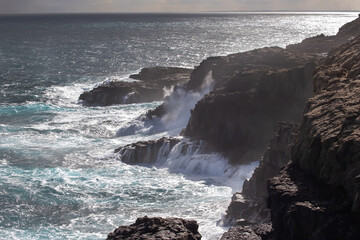 Beautiful ocean landscape, coastline with huge black rocks and big high breaking waves, the power of nature