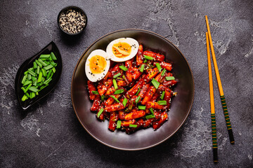 Tteokbokki, Teopokki fried rice cake in black bowl.