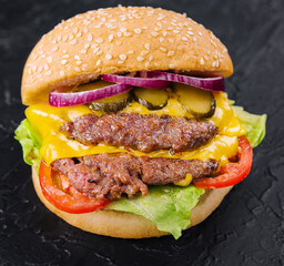 Double patty burger with pickles on black stone