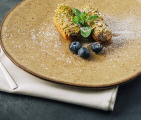 Tasty eclairs with pistachios and cheesecake on plates