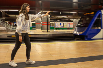 smiling teenage girl in the subway or subway train station listening with her hand outstretched in...