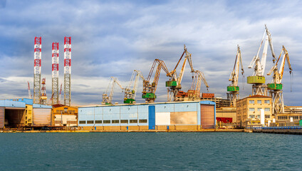 cargo sea port with cranes vehicles, container stacks , supplies and trucks with goods, sea hub...
