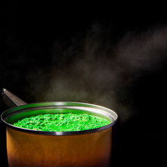 Fototapeta na wymiar Close up of an old cooking pot, with steaming, poisonous looking green porridge. Isolated on a black background