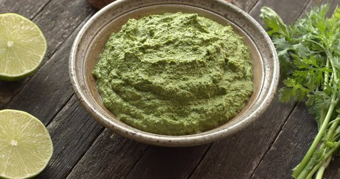Coriander chutney and main ingredients: bunch of cilantro leaves, green chilies, lime and Brazil nuts (shelled and unshelled). Table spin.