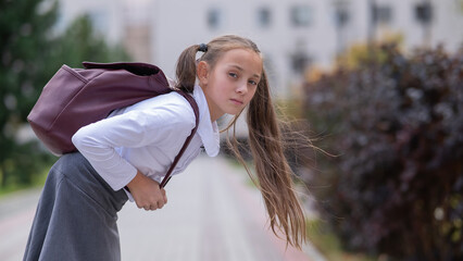 Caucasian girl in uniform and with a backpack goes from school. 