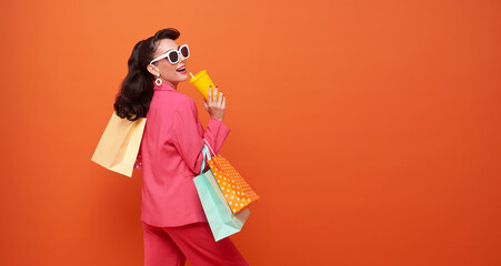Cheerful happy fashionable woman enjoying shopping, she is carrying shopping bags isolated on...