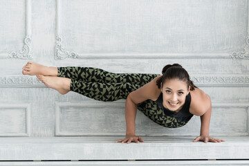 young woman in black sportswear shows yoga asanas and does pilates