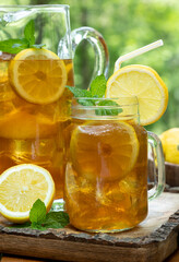 Ice tea in glass and pitcher with lemon and mint
