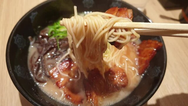 Chopsticks Eating Japanese tonkotsu ramen thick creamy pork bone broth ramen with chashu Tokyo street noodle