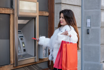 Elegant dressed woman using ATM machine