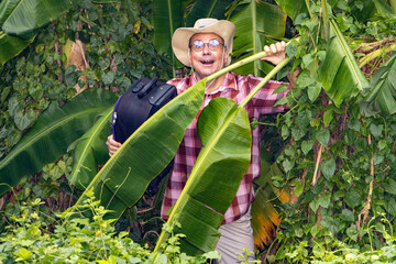 Cheerful tourist with suitcase in tropical jungle