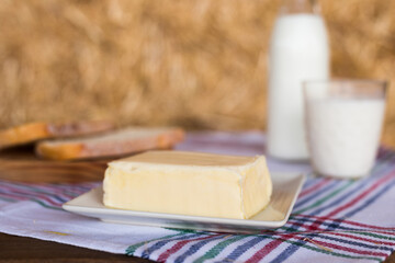 butter, milk, cottage cheese, bread on the table in the barn against background of hay