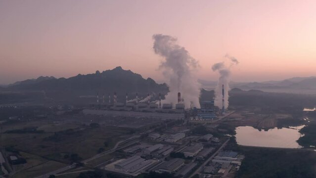 Drone high-angle video footage Coal-fired power plants in the morning, white smoke billowing from cooling and smokestacks.