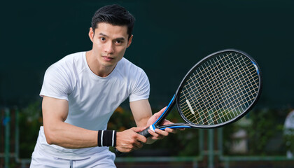 Motivated sportsman in white costume playing tennis on outdoor court. Sport, competition, healthy and active lifestyle concept.