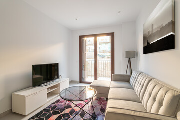 Cozy compact living room with sofa table and TV and decorative accessories with a panoramic window with access to the balcony. The concept of comfortable housing for a single person