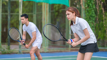 Two focused tennis player in activewear holding racket and aiming at opposite during game.