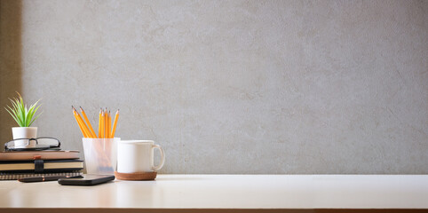 Comfortable workplace with coffee, stationery and houseplant on white table. Home office, copy space.