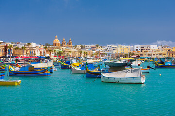 Fototapeta na wymiar Traditional Luzzu fishing boats at Marsaxlokk harbour, a beautiful Mediterranean town in Malta.