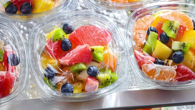 Plastic boxes with pre-packaged fruit salads, put up for sale in a commercial refrigerator