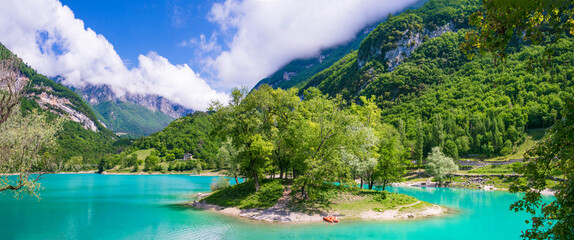 Amazing beautiful turquoise lake Tenno in Trentino region of Italy, surrouded by Alps mountains.  panoramic view with tiny island and canoe