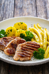Grilled meat and yellow asparagus on wooden table
