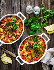 Bread casserole with mozzarella cheese, scrambled eggs, aubergine and tomatoes on wooden table
