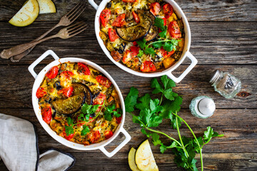 Bread casserole with mozzarella cheese, scrambled eggs, aubergine and tomatoes on wooden table
