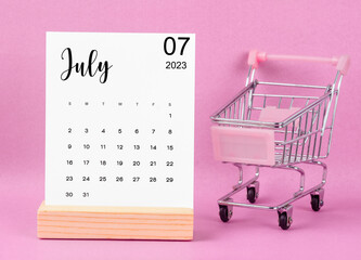 The July 2023 Monthly calendar with shopping cart against pink background.